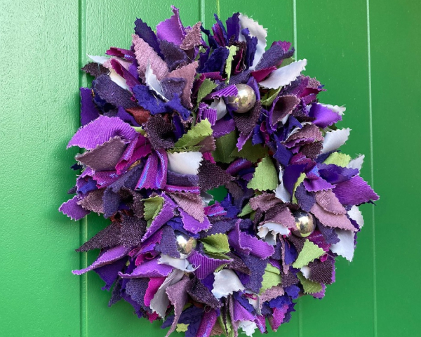 Purple Christmas rag rug wreath hanging on a bright green door
