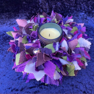 a purple rag rug table decoration with a candle in its centre